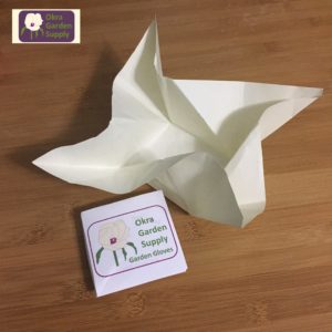 Photograph of an unfolded origami Menko fold in cream paper on a wooden table